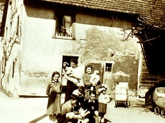 Haus Brucker in der Kirchstrasse. Hinten Reben und Steinbruch. Herrmann Brucker, Sattlermeisterca 1938, Schreinermeister Stöcklin vorne in schwarzem Pullover;in der Tür Rosine Brucker, mit Baby Frau Albiez  
Bild45